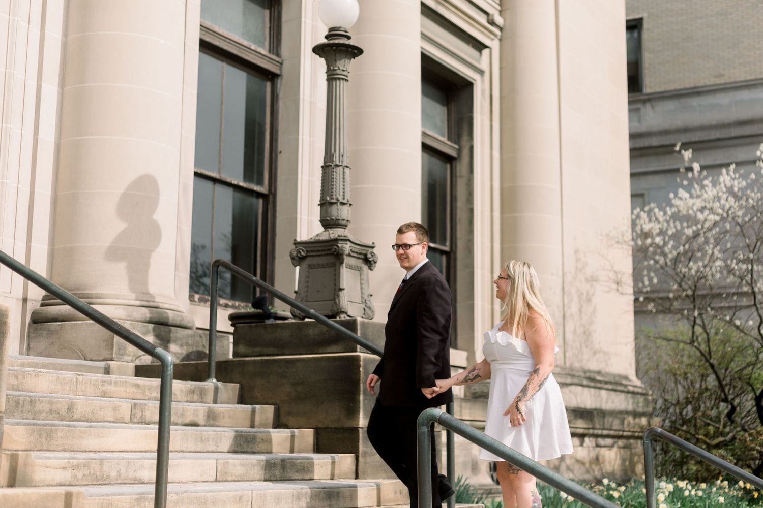 A couple poses on elegant stone steps with architectural columns in the background.