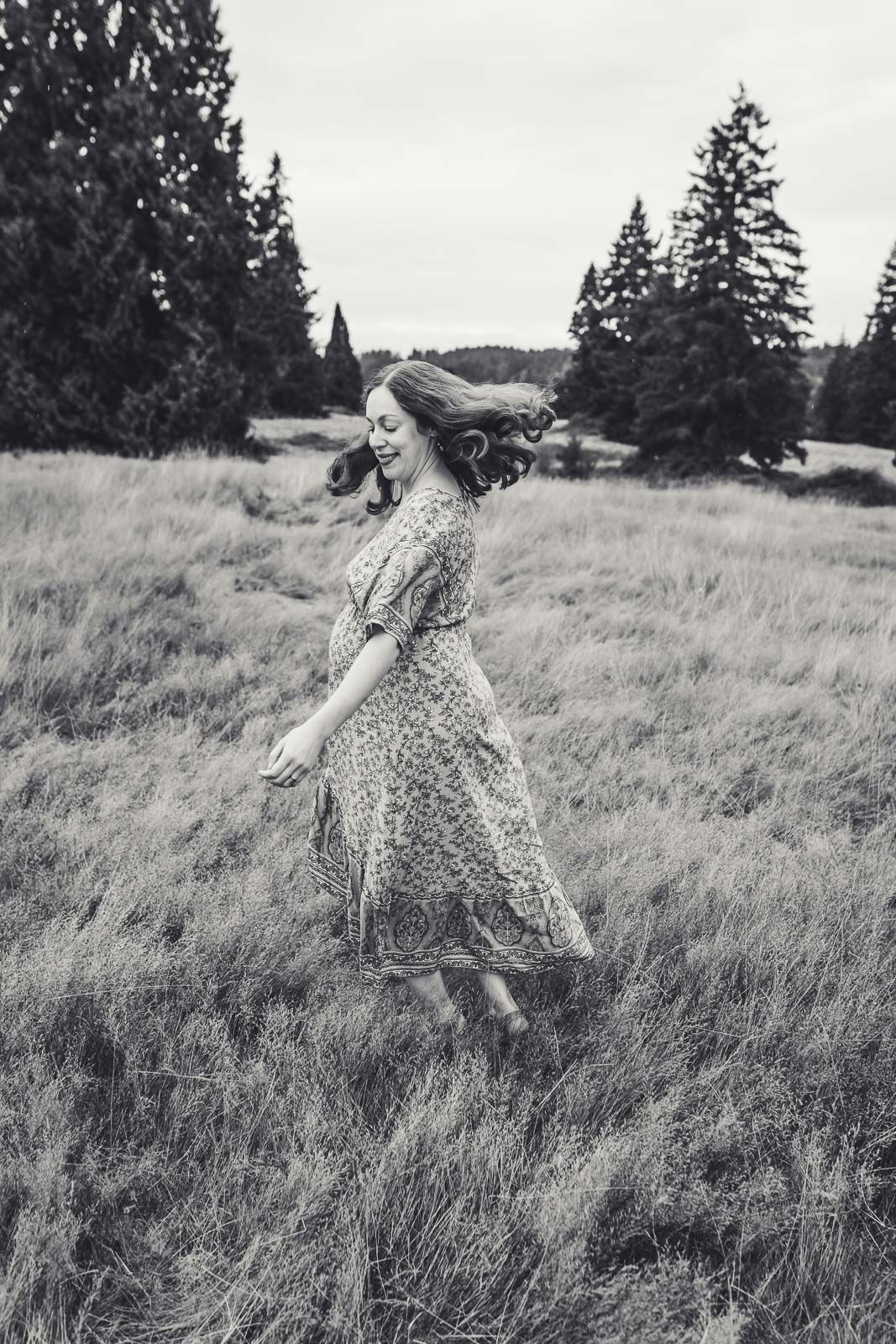 Black and white photo of pregnant mom twirling in a field
