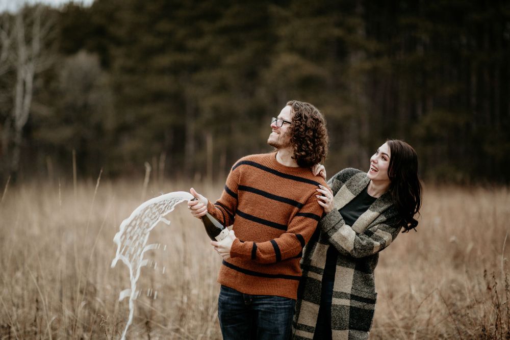 Happy couple hugging and smiling in a dry autumn meadow surrounded by tall brown grass.