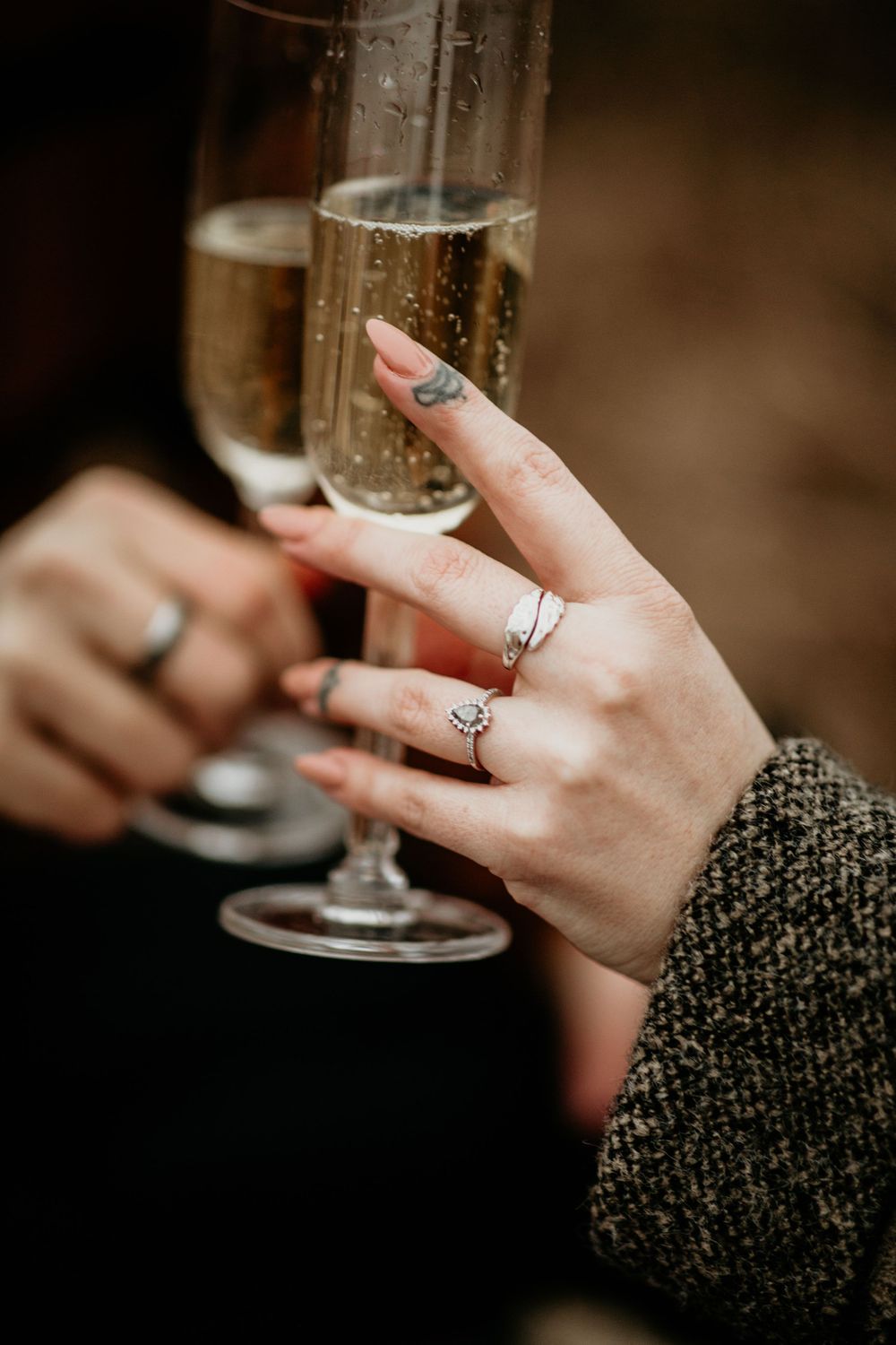 Close-up of engagement ring and wedding band on woman's hand holding a champagne flute.