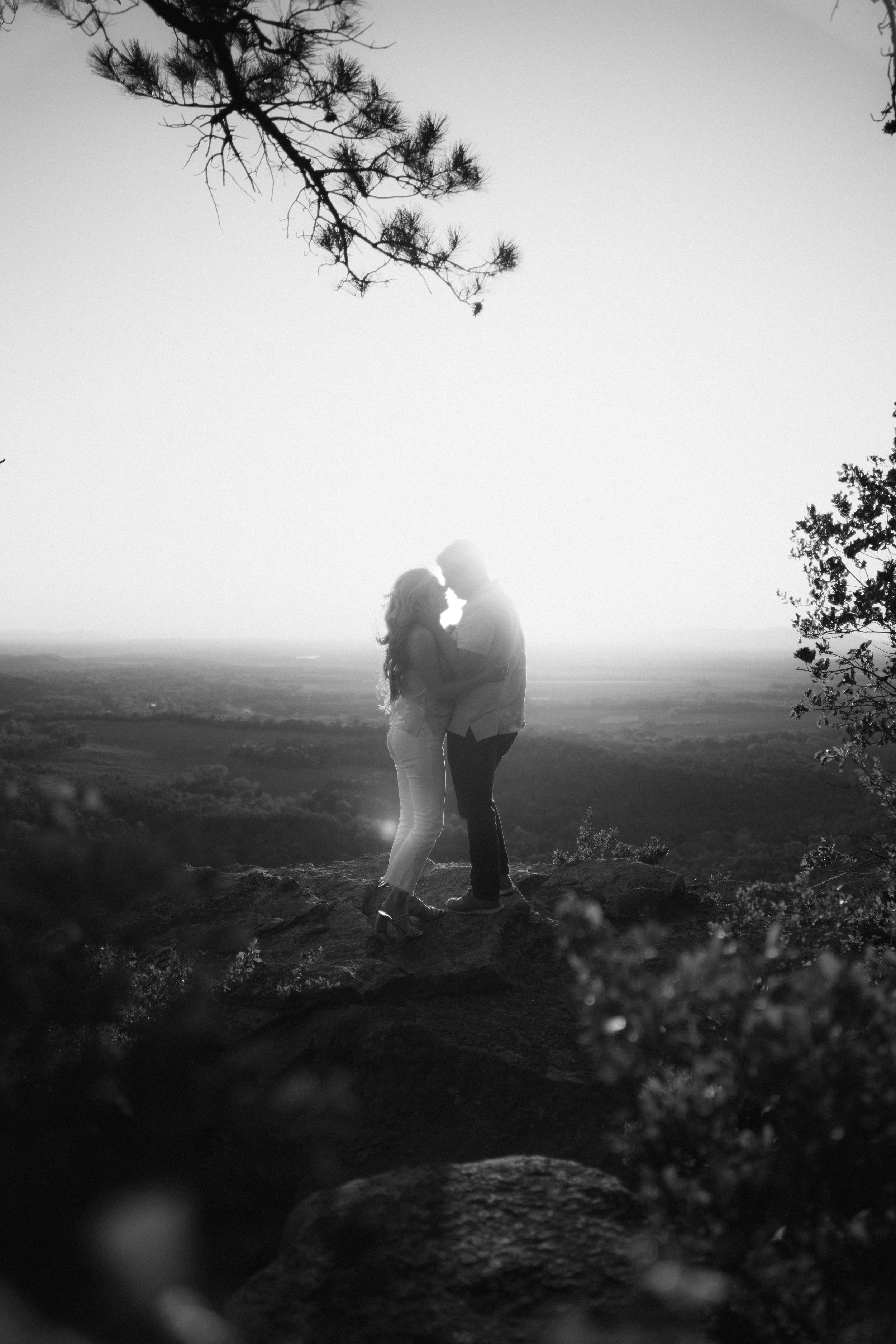 Silhouetted figures standing on a hilltop against a dramatic black and white skyline.