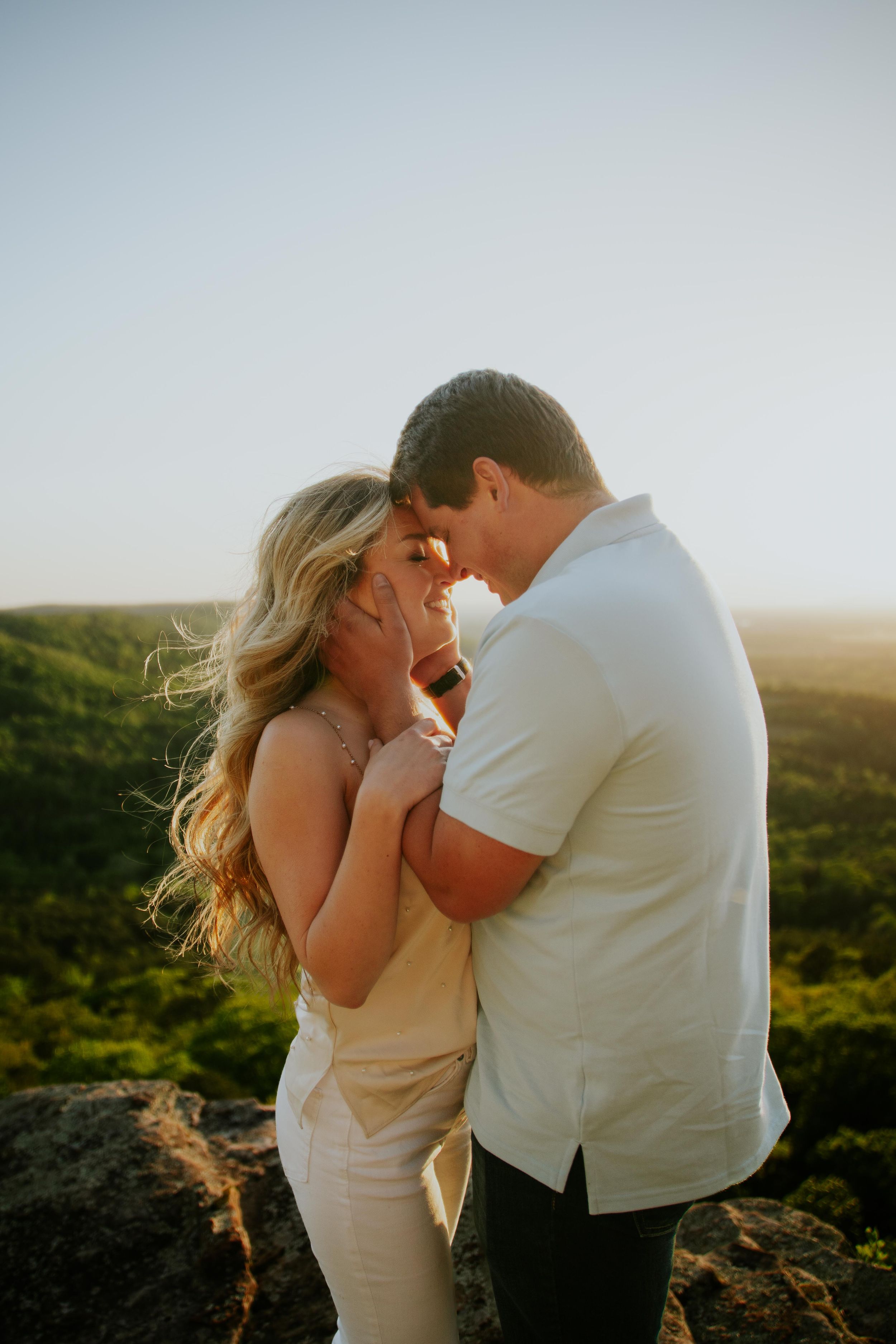 Intimate moment between couple on clifftop during golden hour.