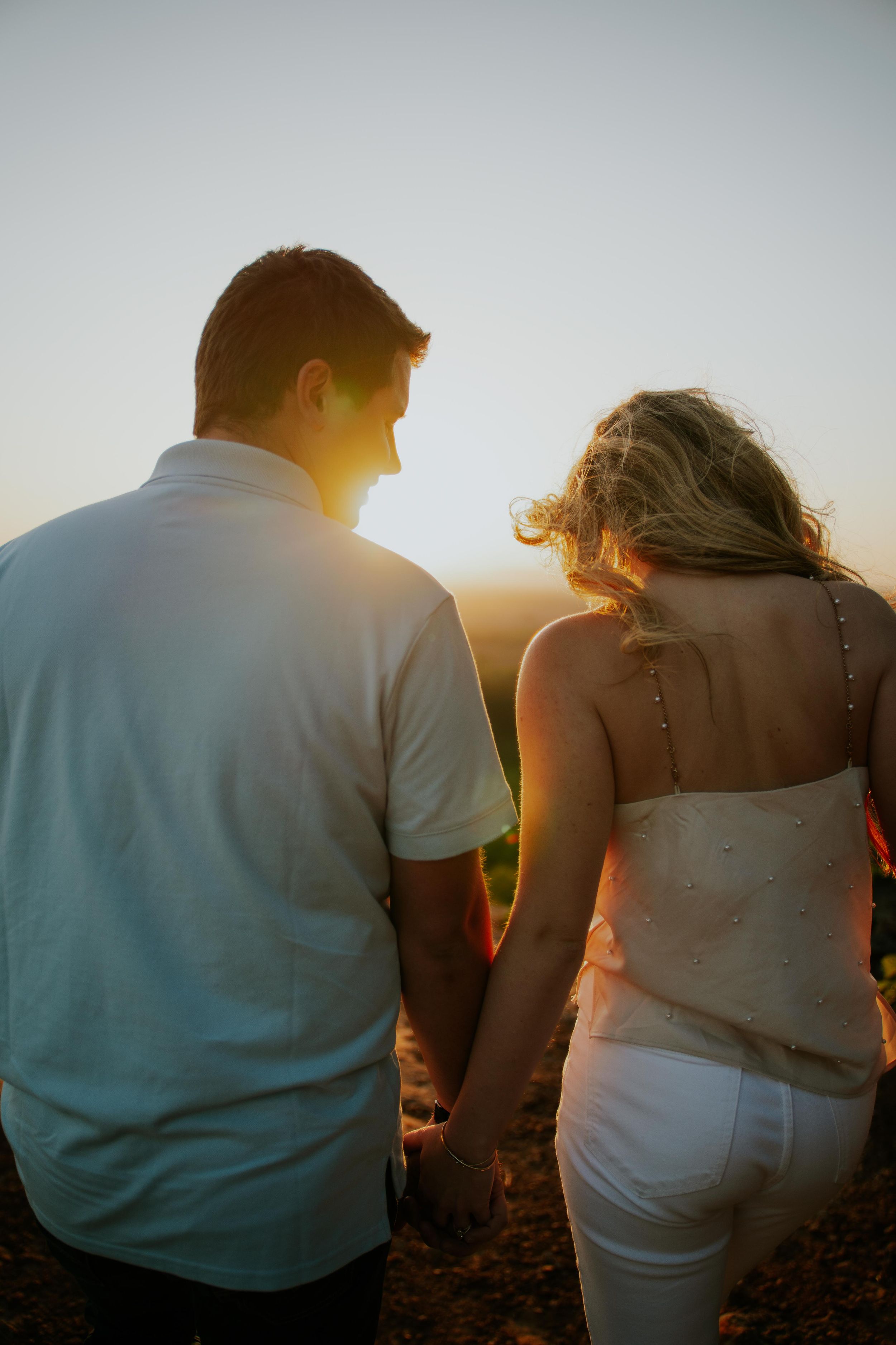 Couple walking together against golden sunset sky.