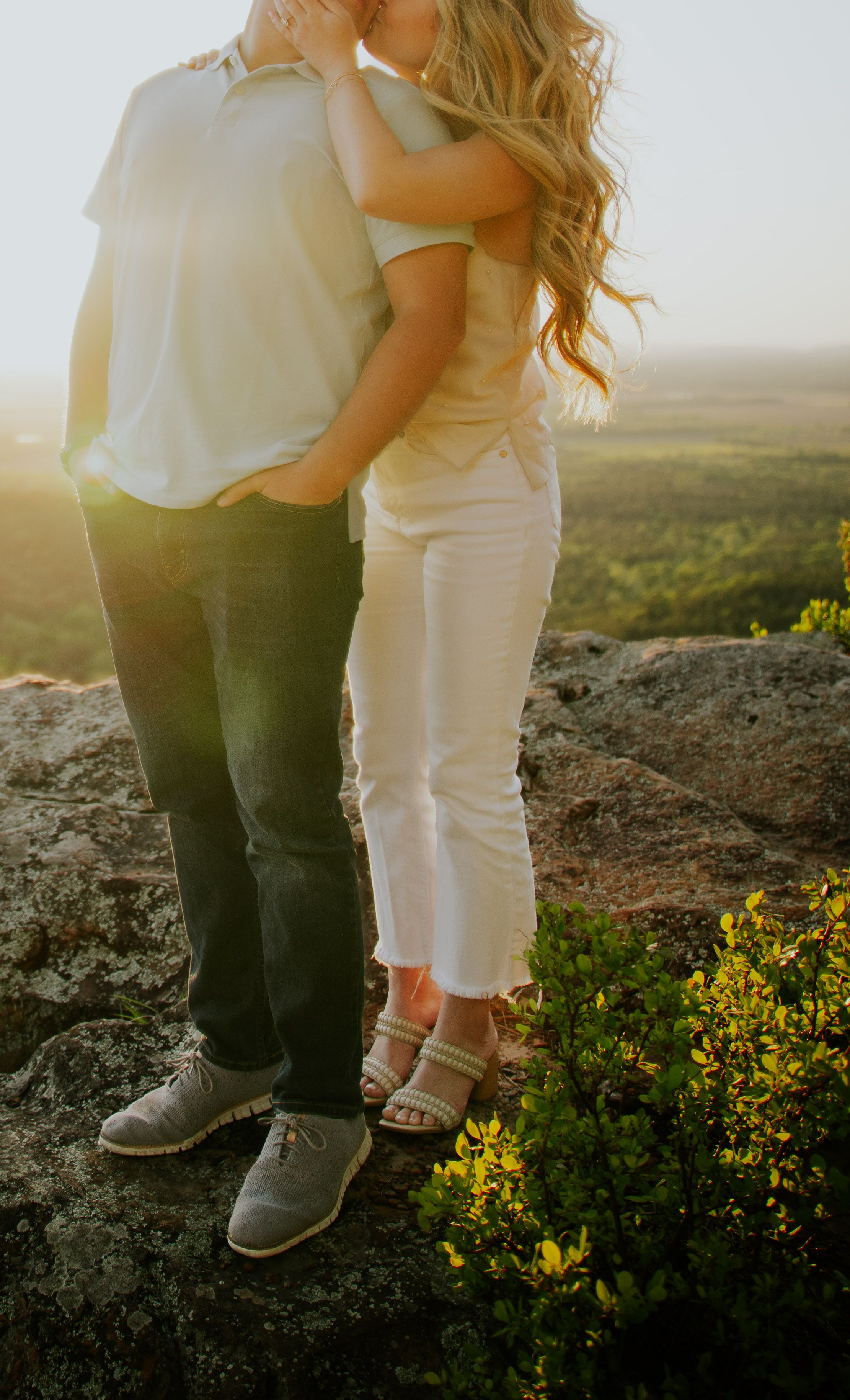 Close-up shot of legs and feet standing on rocky terrain with yellow wildflowers.