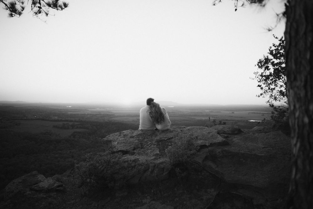 A romantic black and white landscape photo featuring a couple silhouetted against a misty backdrop.