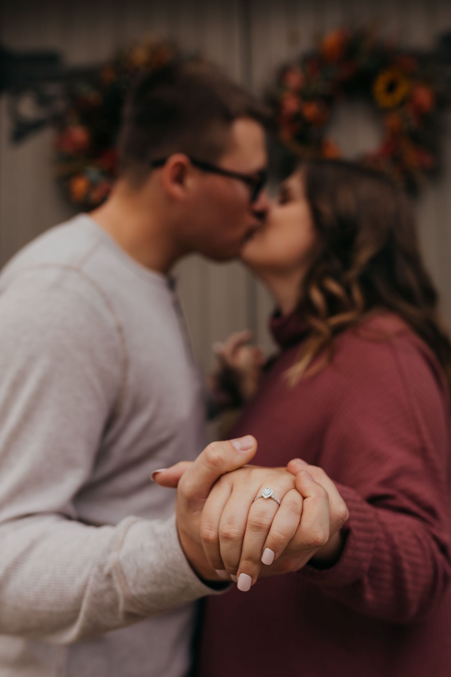 Close-up of couple's hands showing engagement ring while sharing intimate moment.