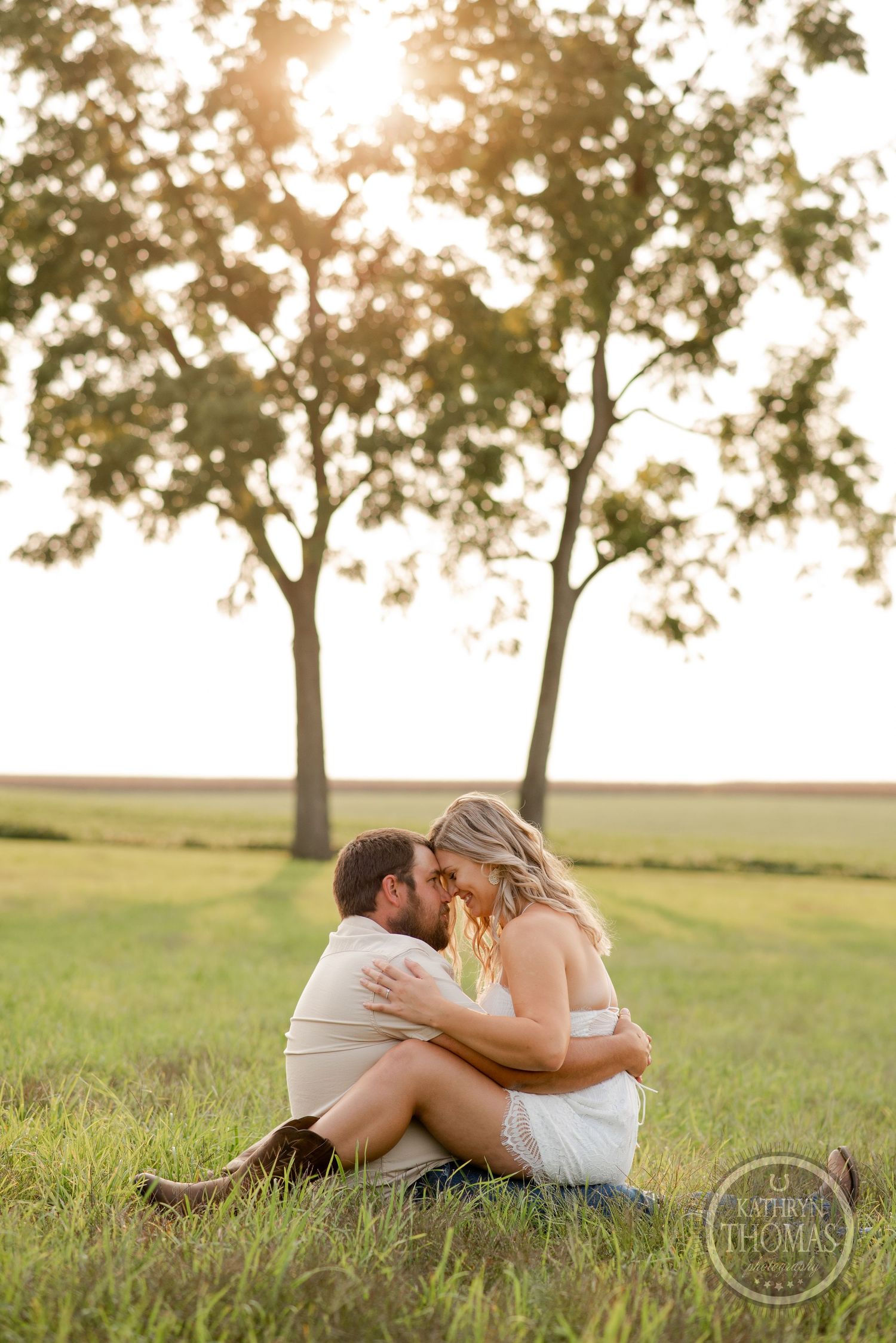 A romantic sunset moment captured as a couple sits together in tall grass.