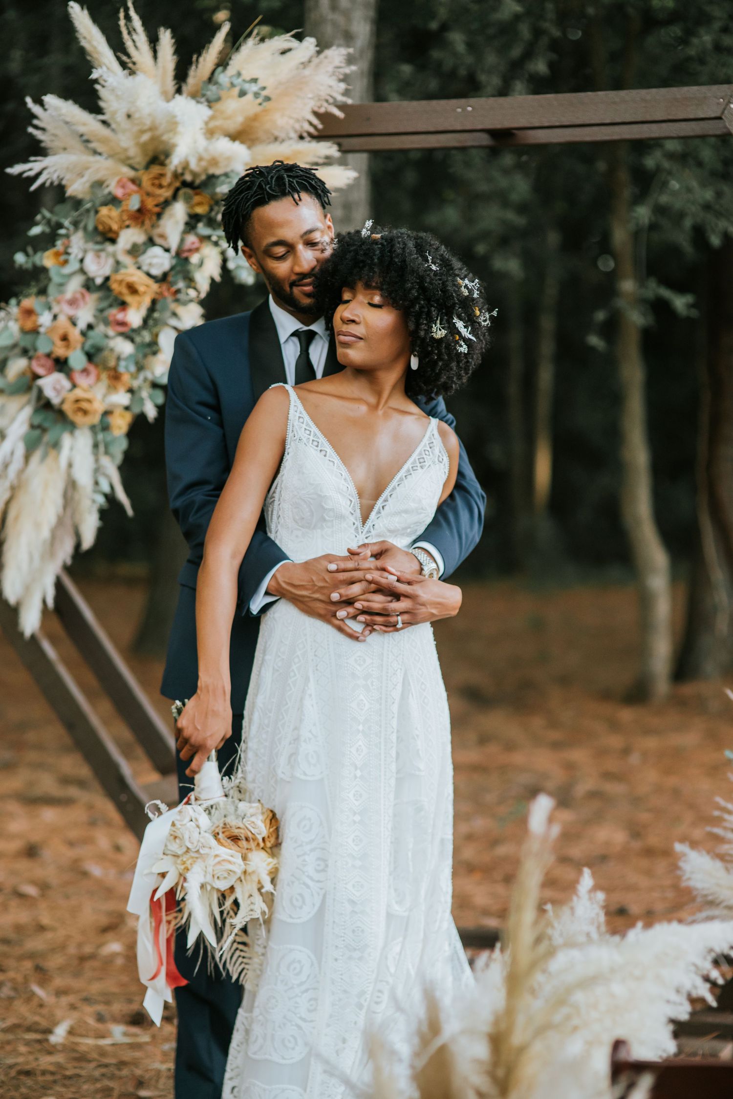 BIPOC Wedding Couple embracing each other in front of a floral altar backdrop