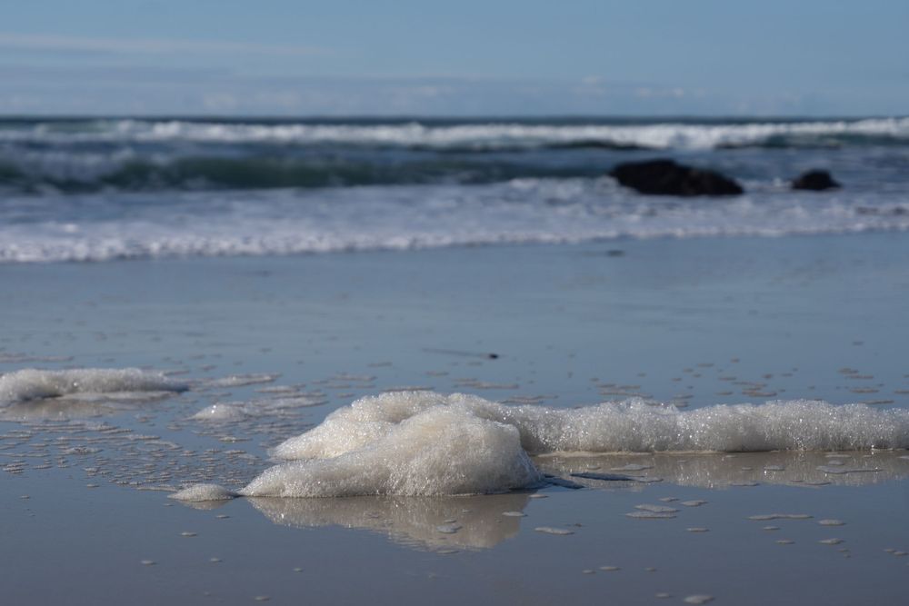Tranquil beachscape with waves lapping at the shore under a cloudy sky.