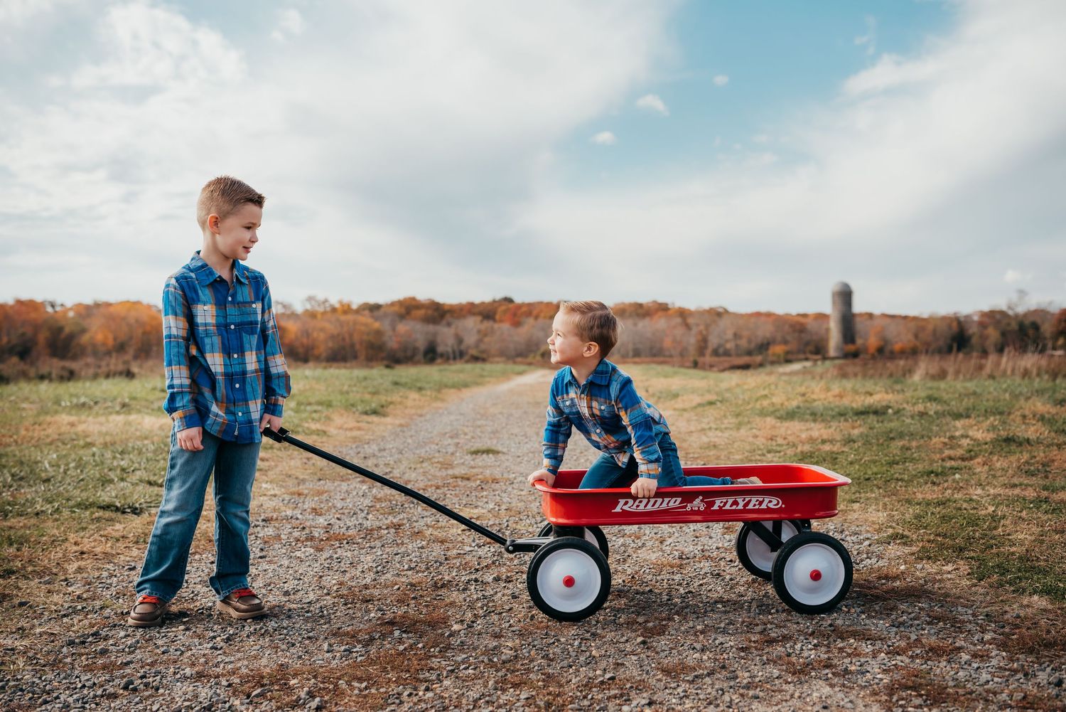Two brothers play on a red wagon at a Silo Farm.
