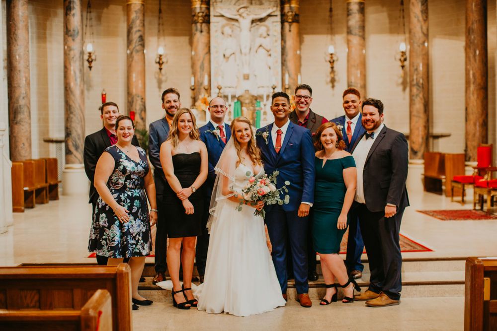 Wedding party group photo with bride and groom inside church after ceremony.