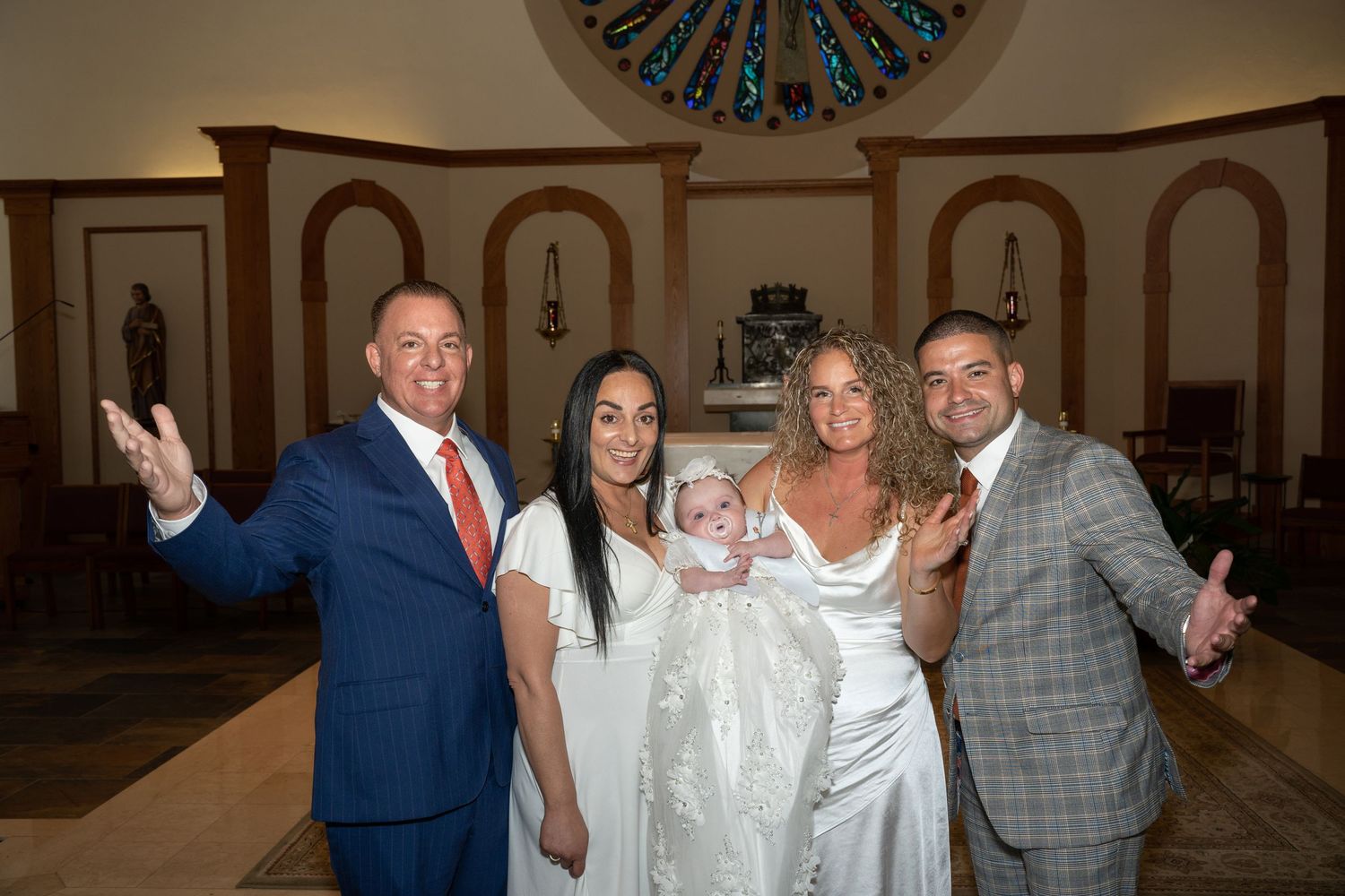 Church interior with decorative stained glass window and family members gathered for ceremony.