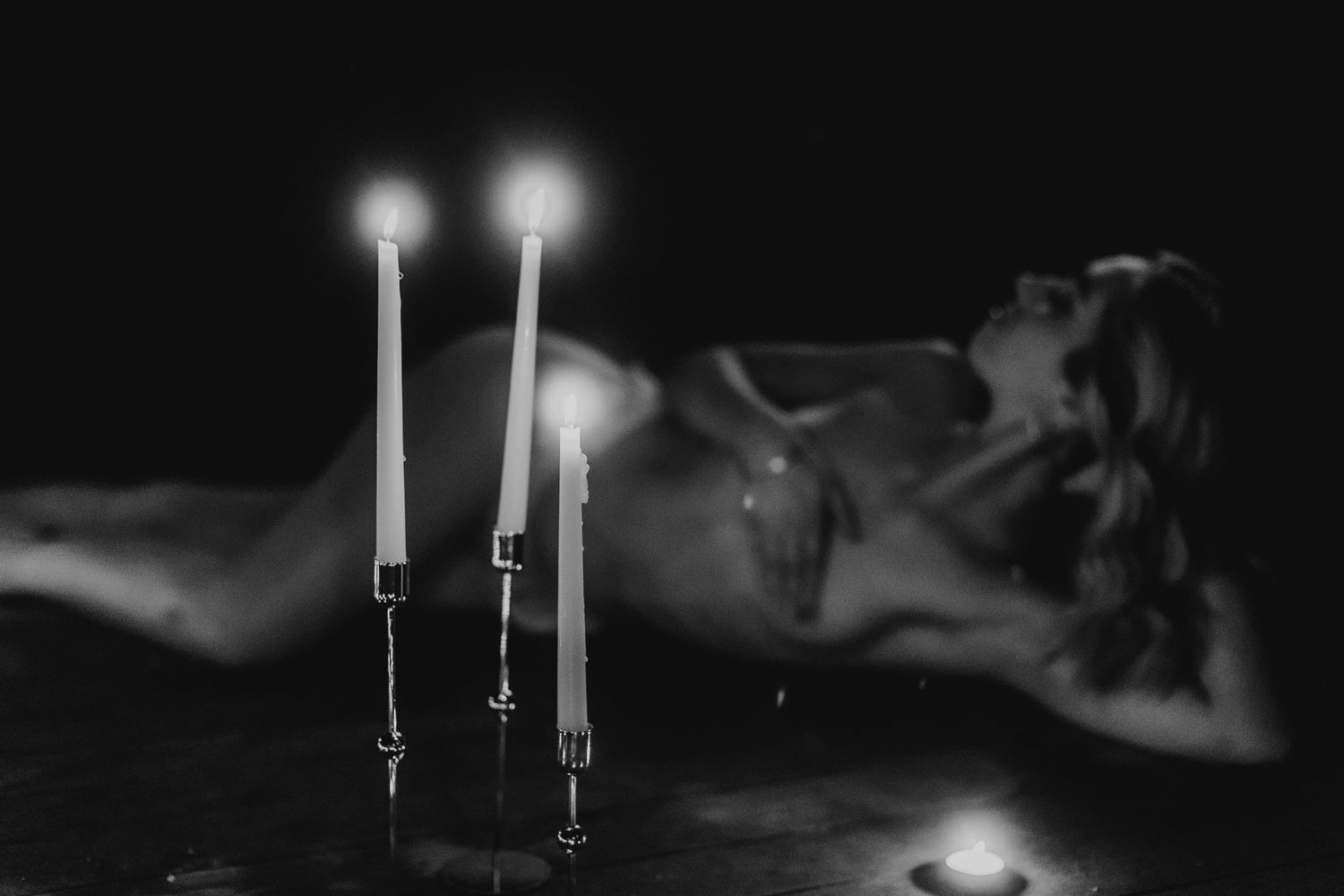 Black and white out of focus nude woman in front of candles