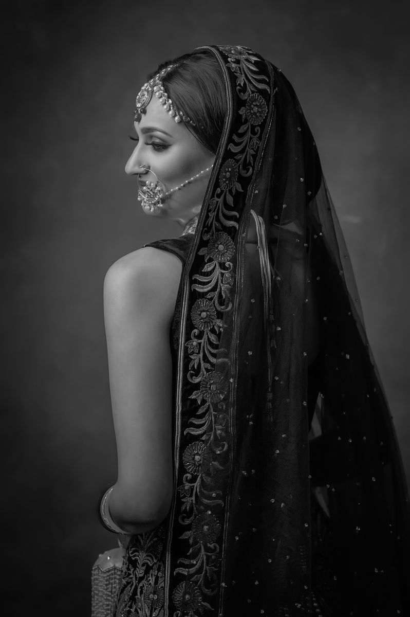 Black and white profile portrait of bride wearing intricate traditional Indian veil and jewelry.