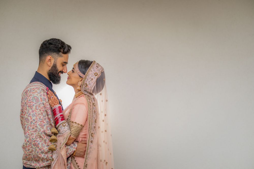Romantic couple in traditional South Asian wedding attire share an intimate moment.