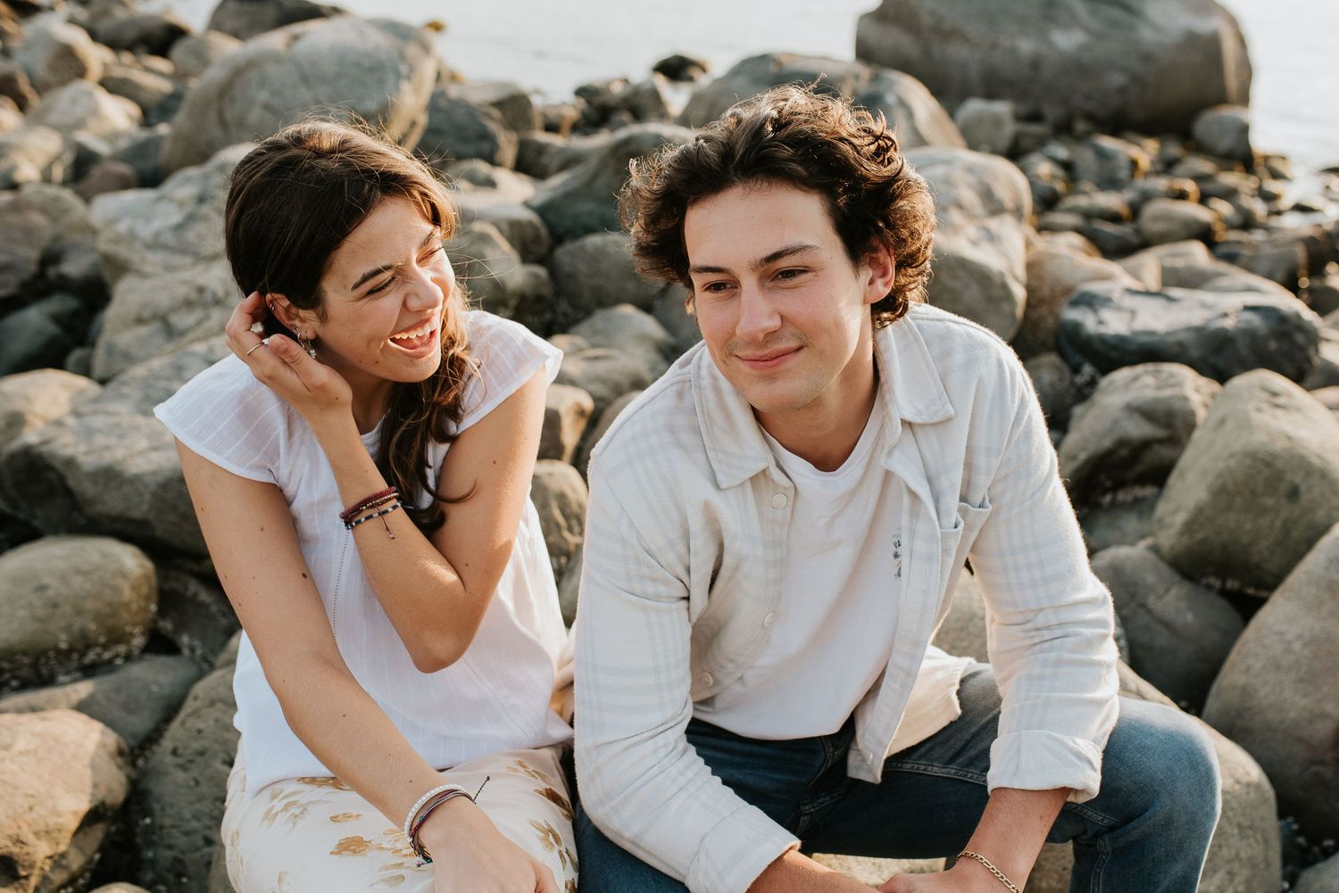 Two teenage siblings sitting on rocks at Whitecliff Park laughing