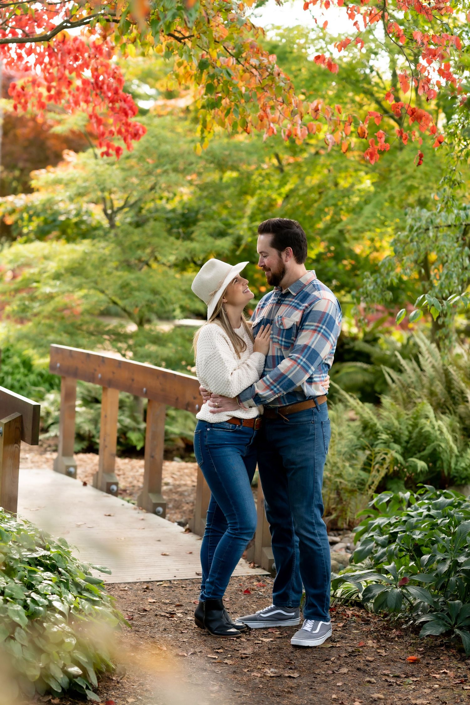 Couple sharing romantic moments among vibrant fall foliage in a garden setting.