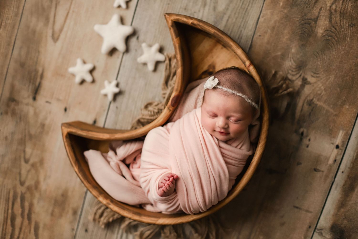 Newborn baby girl portrait in studio moon bowl prop with stars in pink