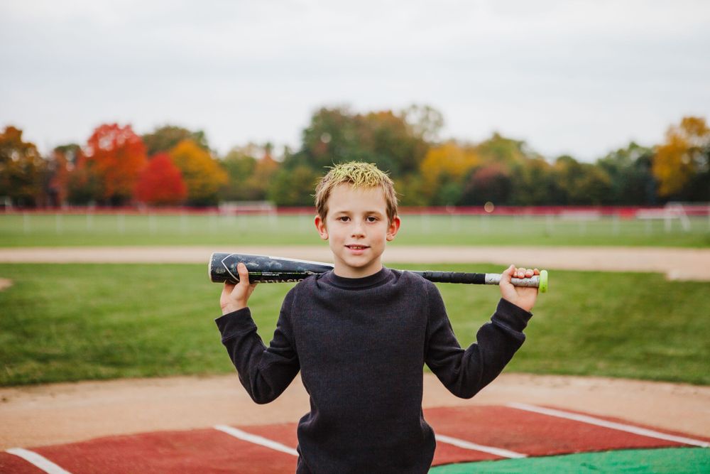 An athletic field with autumn trees in vibrant fall colors provides a backdrop for sports activities.