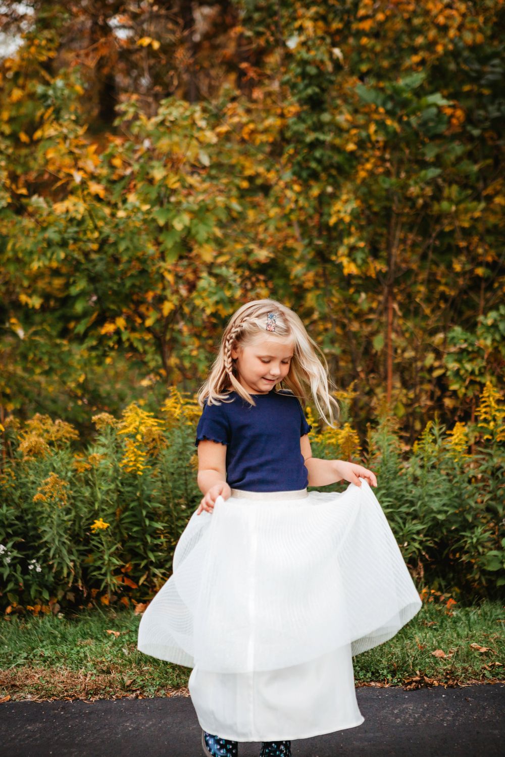 Beautiful fall foliage creates backdrop for figure in navy and white dress.
