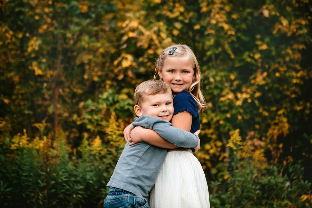 Autumn scene with golden leaves in background during outdoor portrait session.