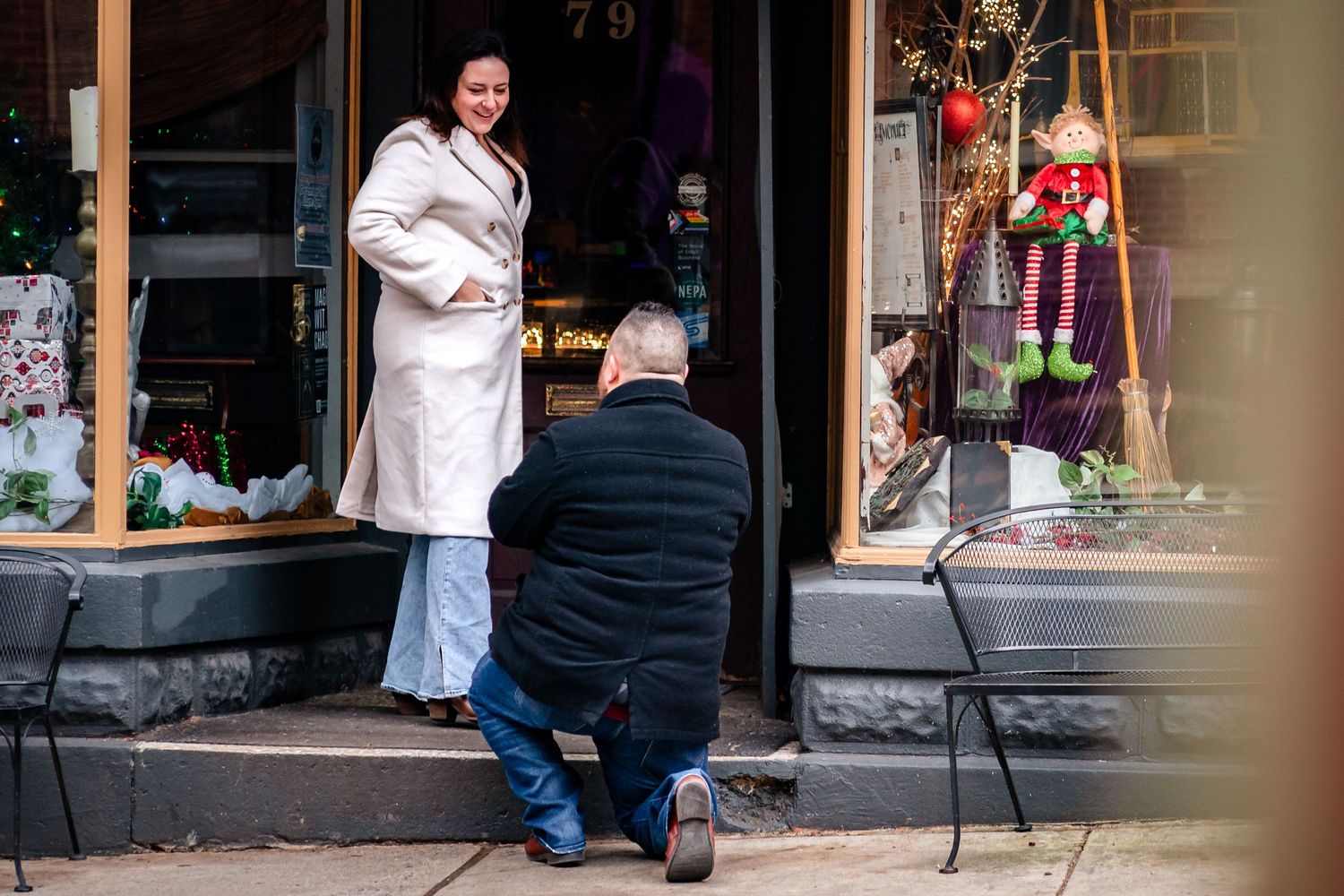 People walking past storefronts and window displays along a shopping street.