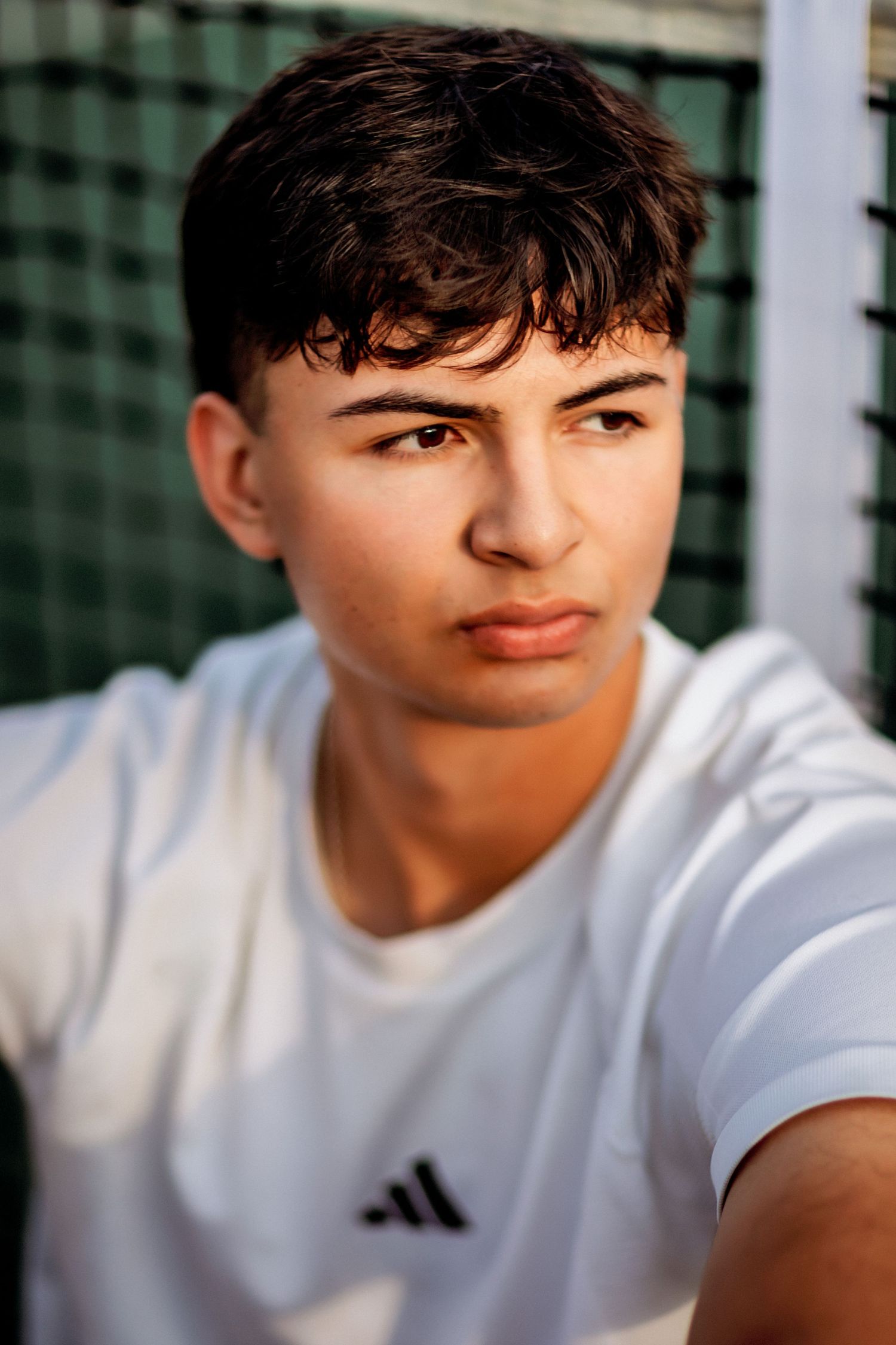 Athletic portrait against green background showing person in white Adidas shirt in Pensacola Florida