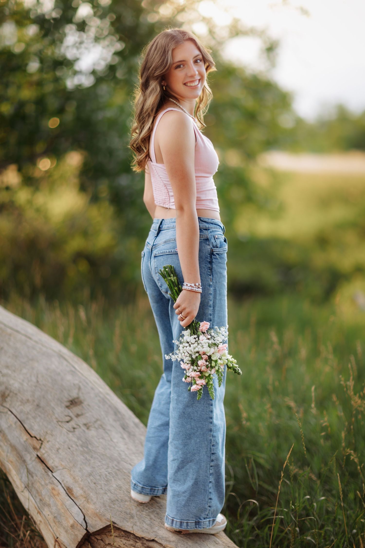 Woman in casual summer outfit holds wildflowers during golden hour outdoor photoshoot in Destin, FL
