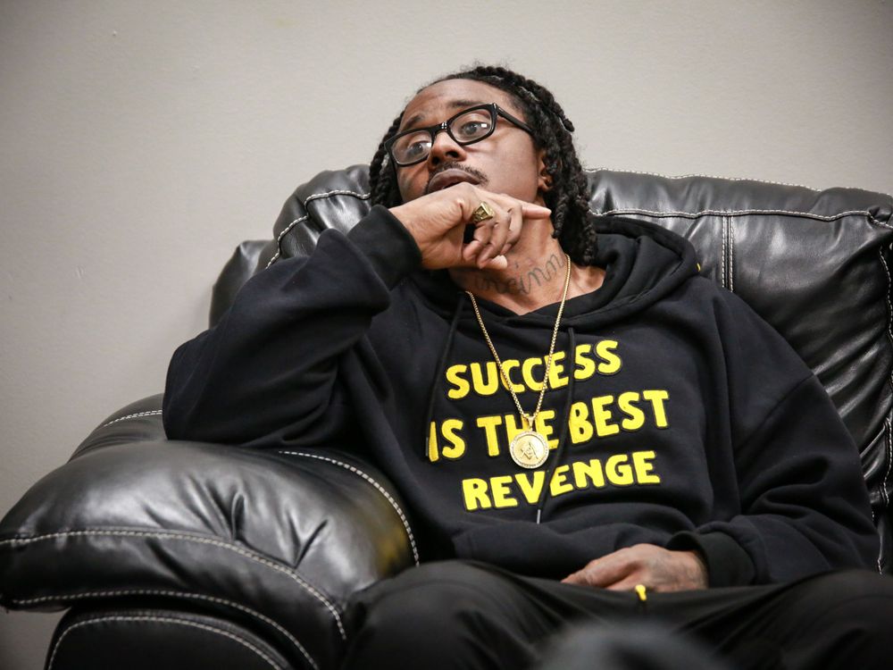 Person wearing black hoodie with 'Success is the Best Revenge' text relaxes on leather couch.