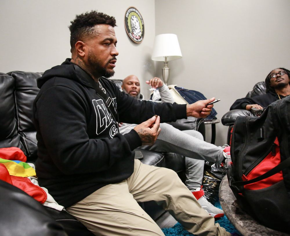 Three people relaxing on a couch engaged in casual conversation in a living room setting.
