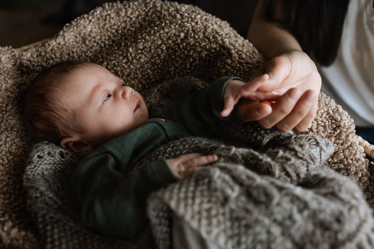 Close-up series of baby sleeping peacefully in knitted blanket.