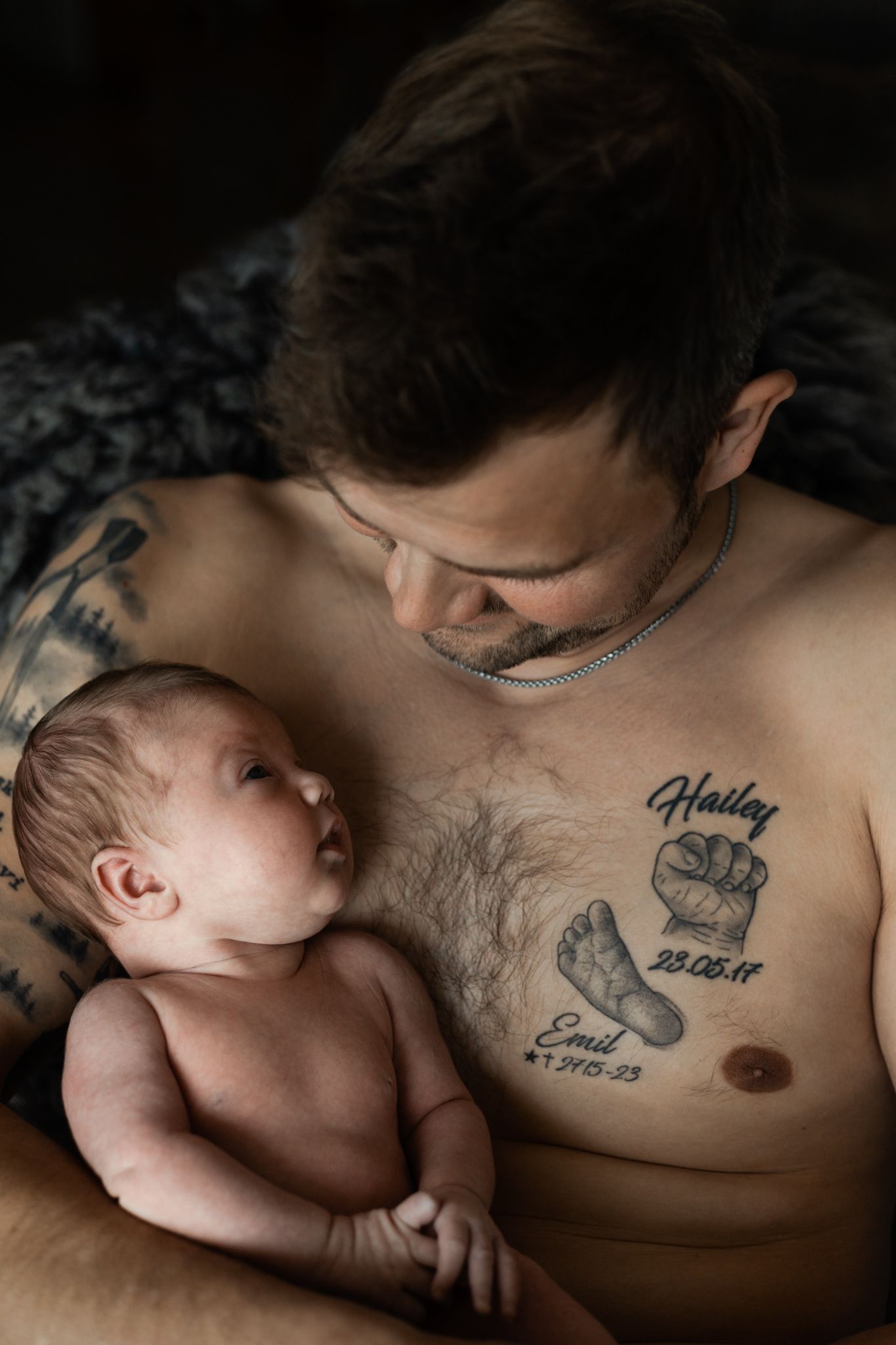 Intimate black and white photos showing a baby resting on a tattooed chest.