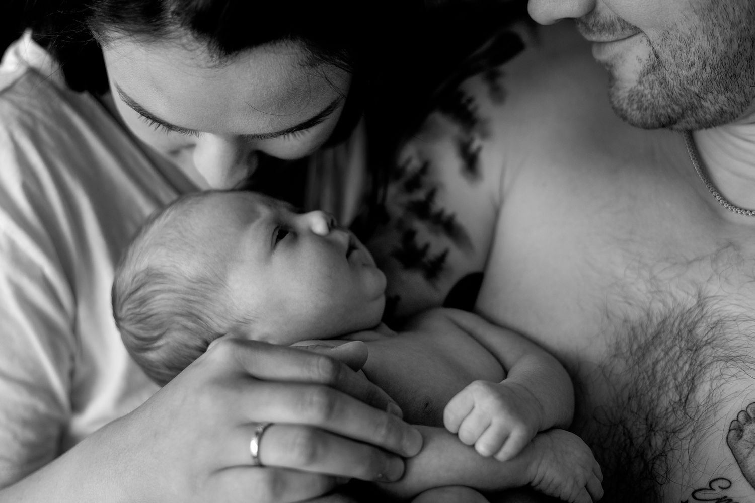 Intimate black and white portraits of parent bonding with newborn.