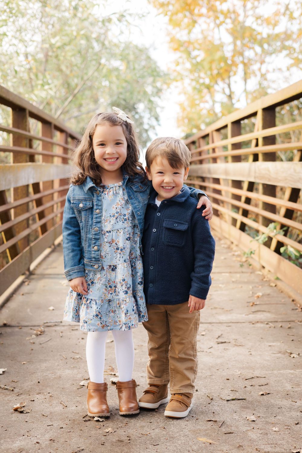 two young siblings standing together on a bridge for a family photo session in fall at golden hour. Santa Rosa. Sonoma County.