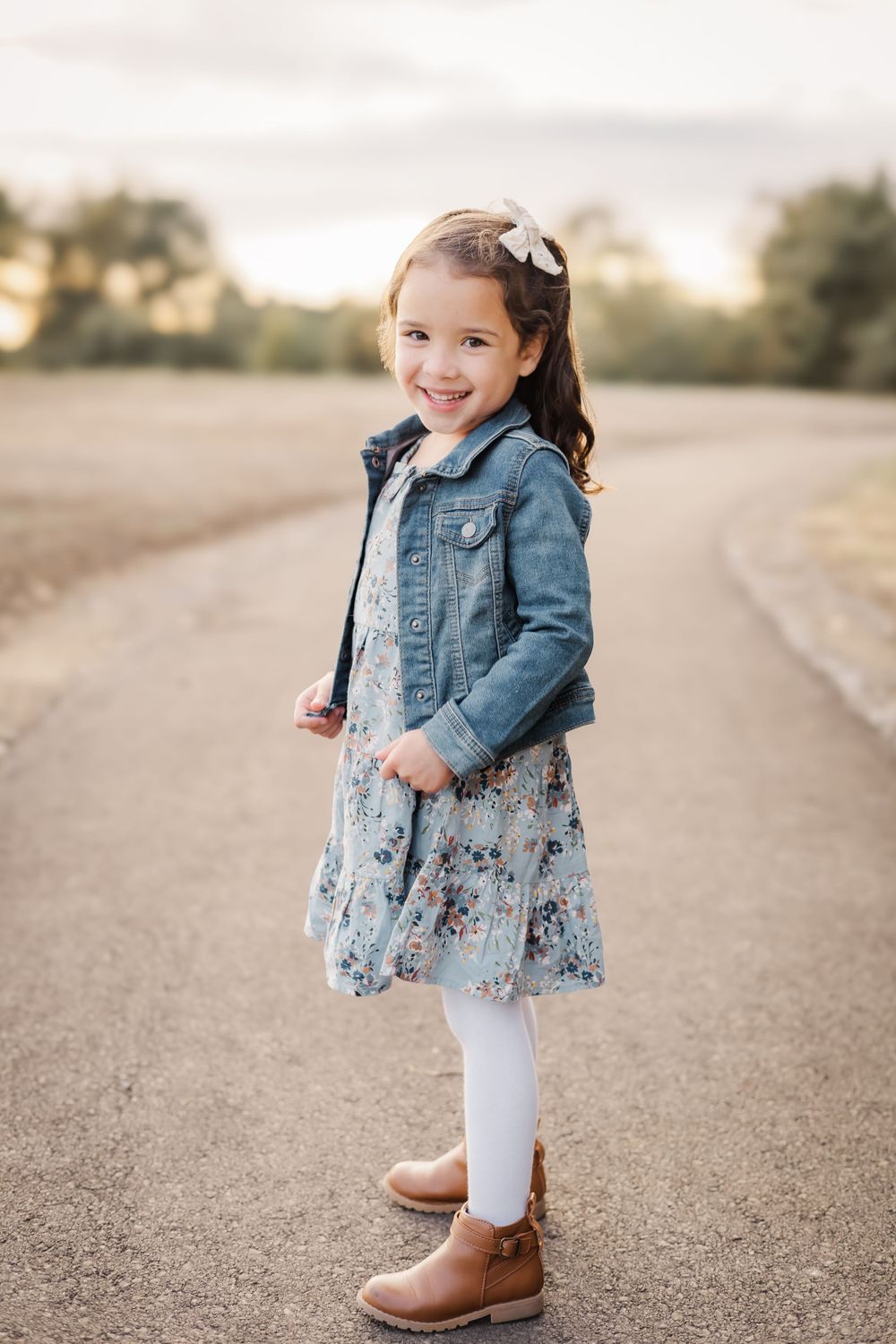 five year old girl posing in outdoor photo shoot at golden hour wearing floral dress and jean jacket. Sonoma county