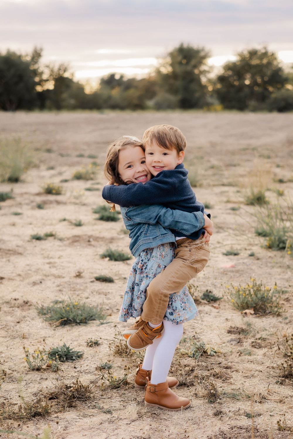 two toddler sibling hugging in an open field at golden hour for a fall mini session in Sonoma County California