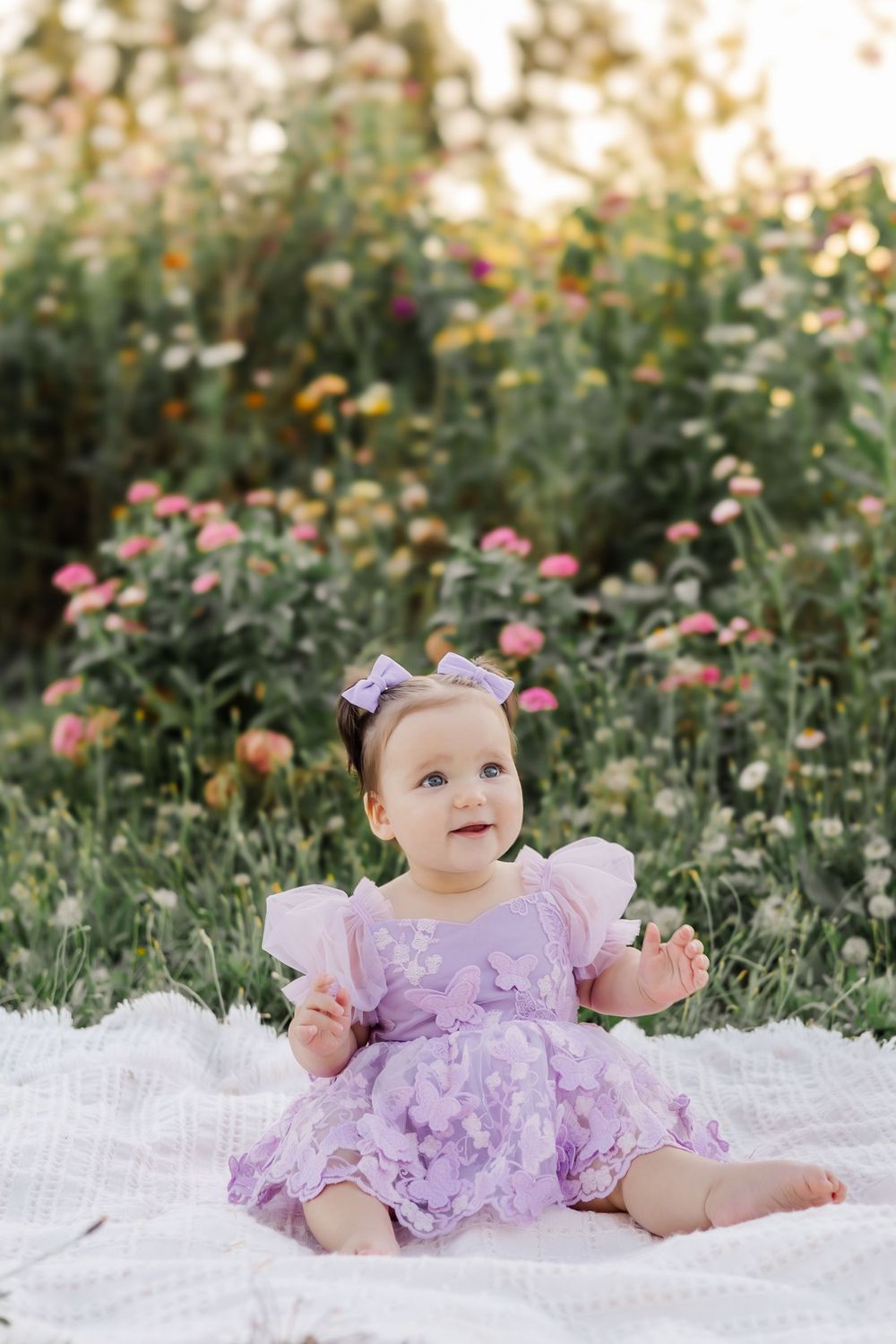 1 year old baby sitting up on a blanket in a beautiful purple dress. in a garden at golden hour in Sebastopol, Sonoma County.