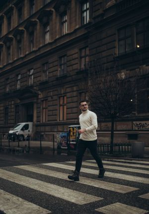 Stylish winter street scene with person crossing zebra crossing in cream sweater.