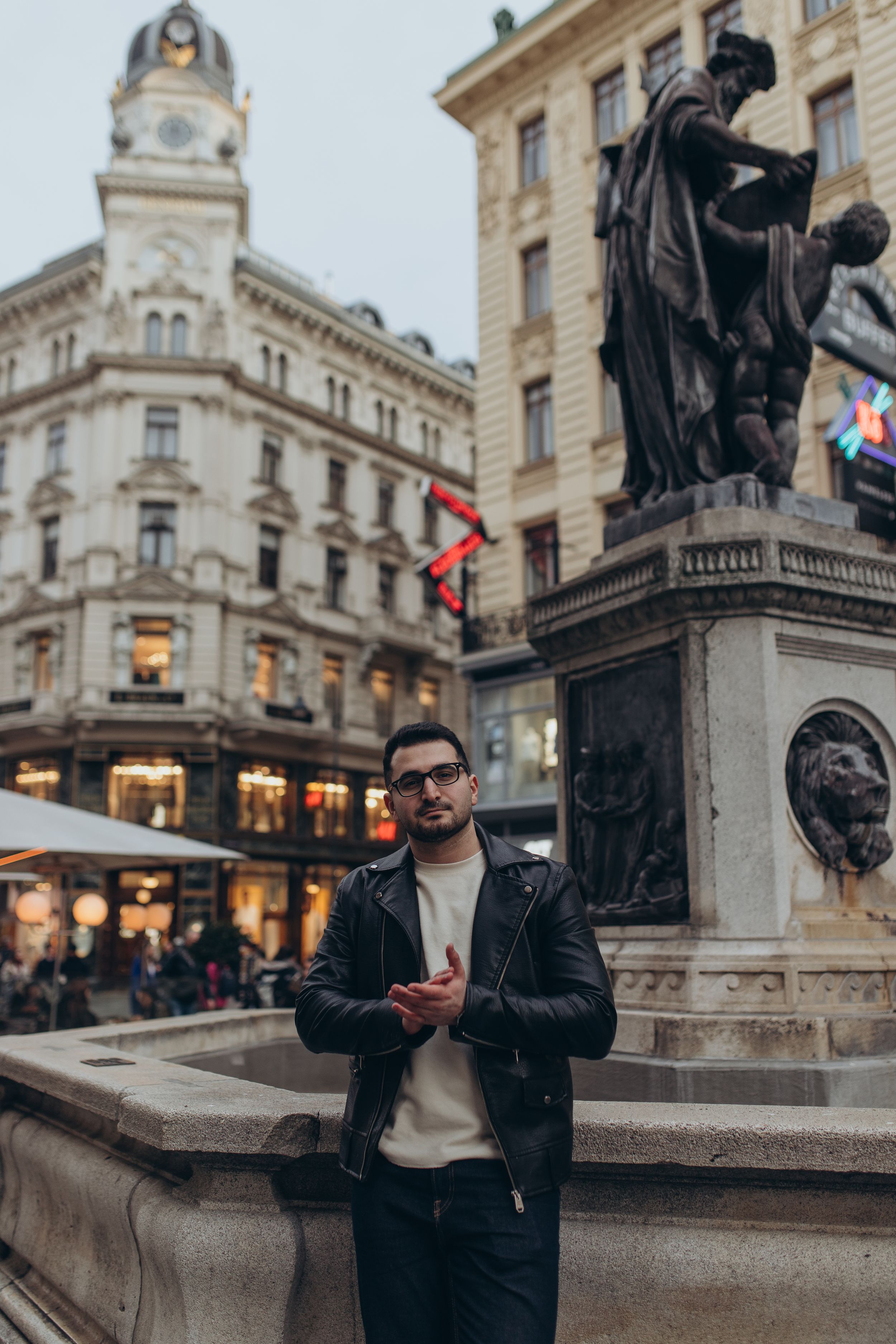 Urban street scene in Vienna with historic buildings and classical statue monument.