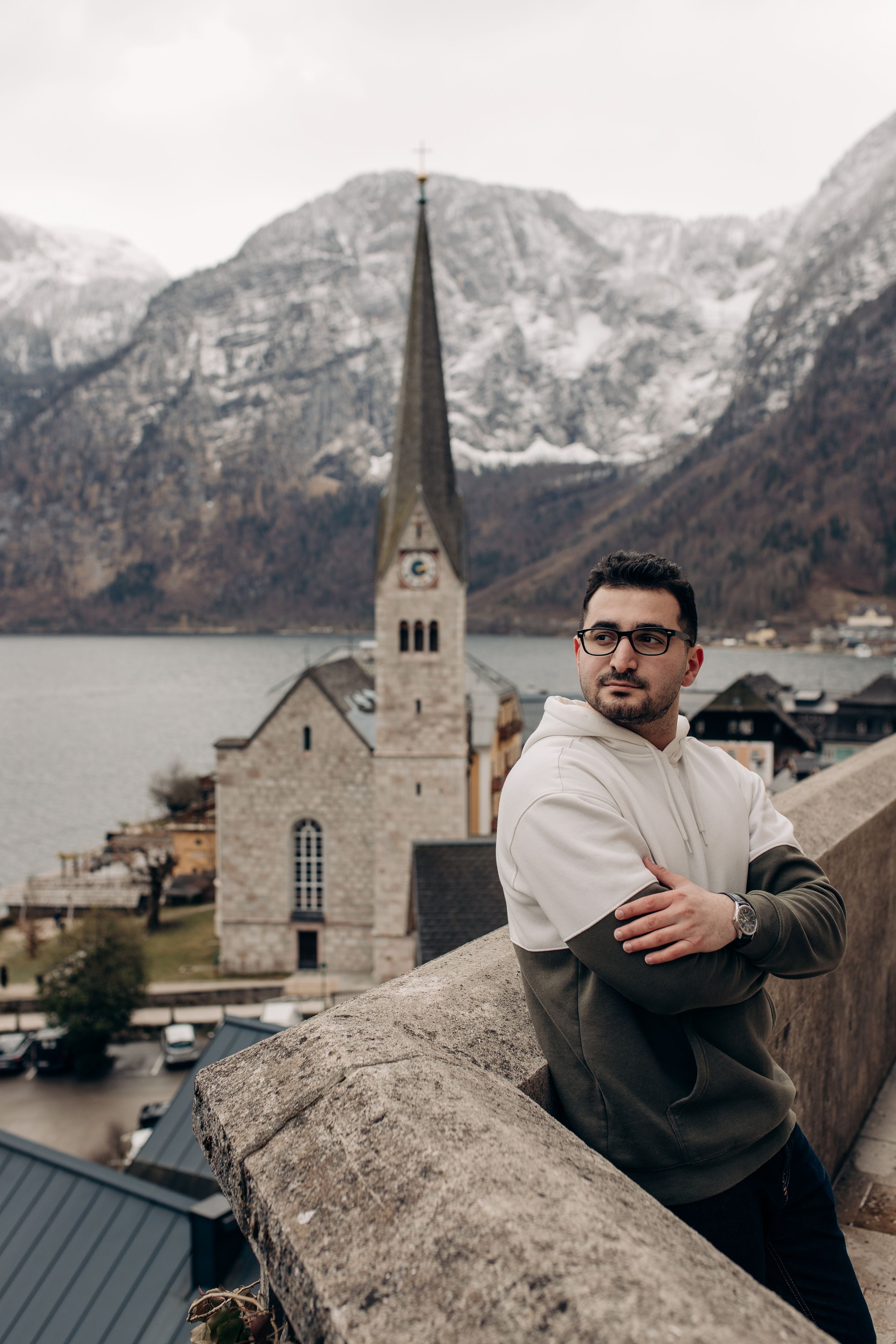 Scenic view of Hallstatt church spire against mountain backdrop with person in foreground.