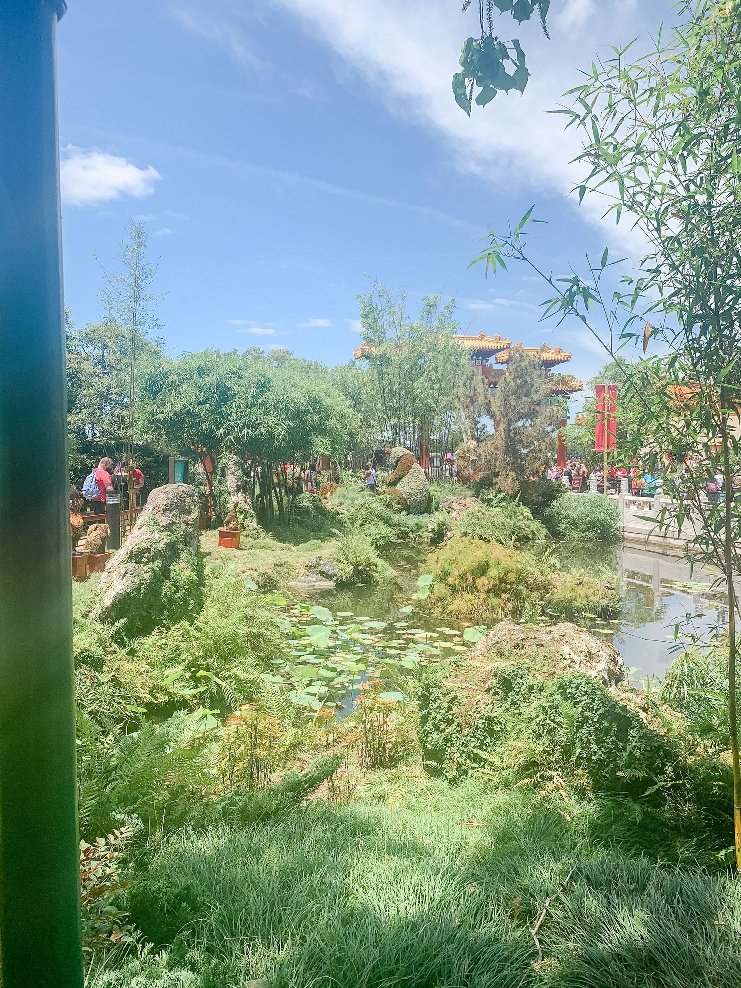 Serene garden landscape with lily ponds and Asian architecture visible through the trees.