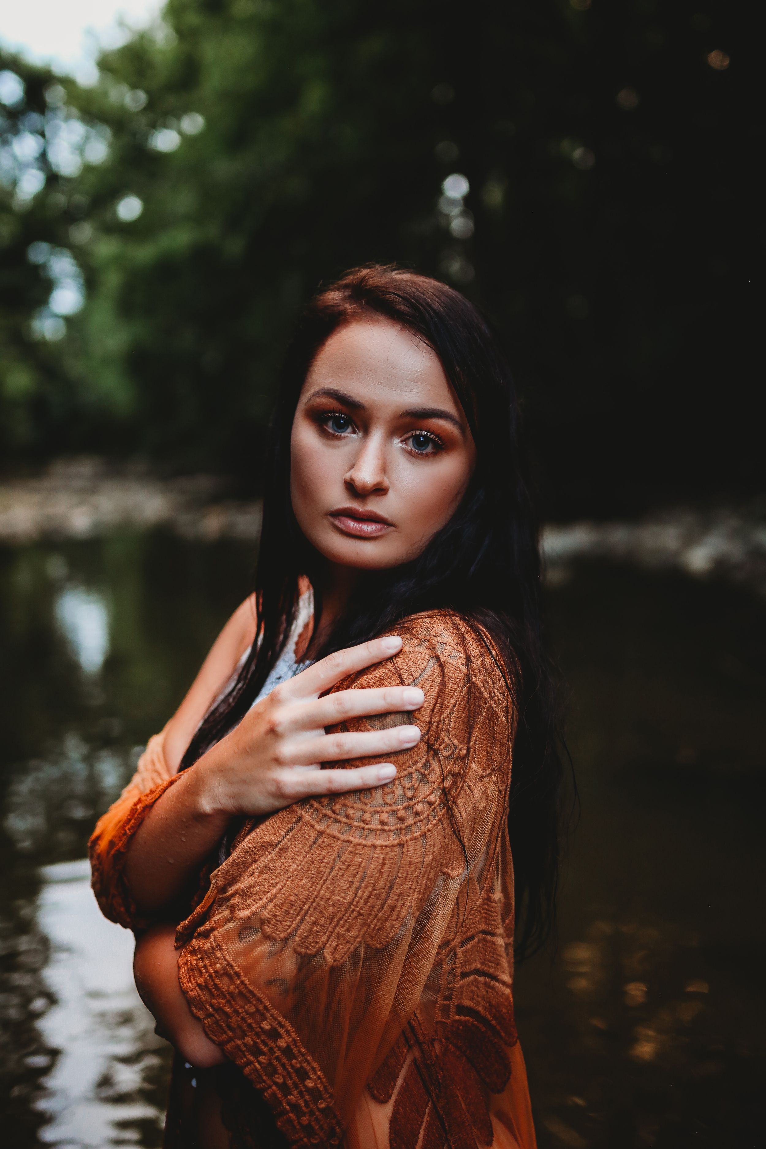 Woman in lace dress poses artistically in dark moody water with textured lighting.