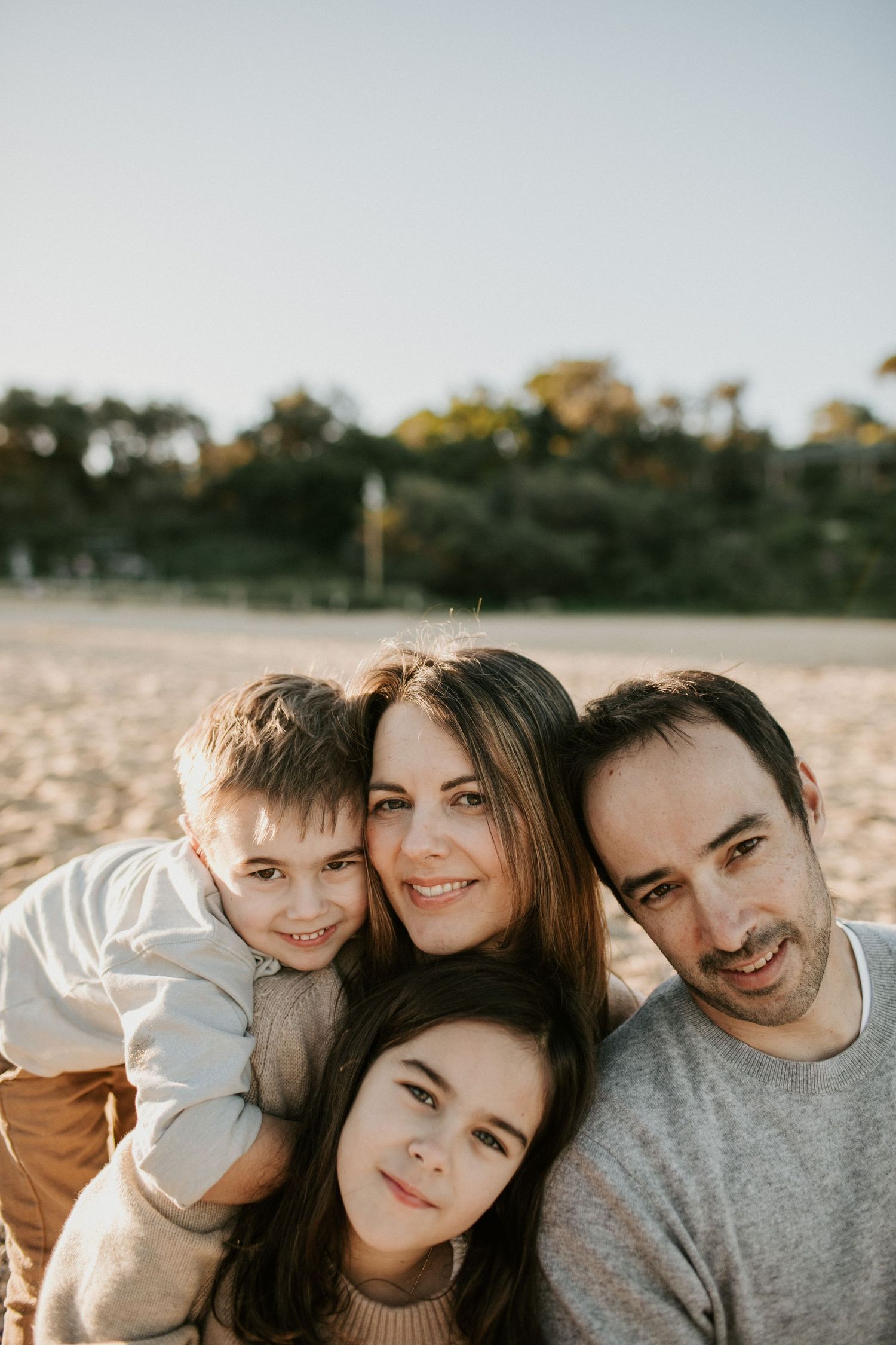 Close-up portrait of smiling family of four on a beach, parents with two children.