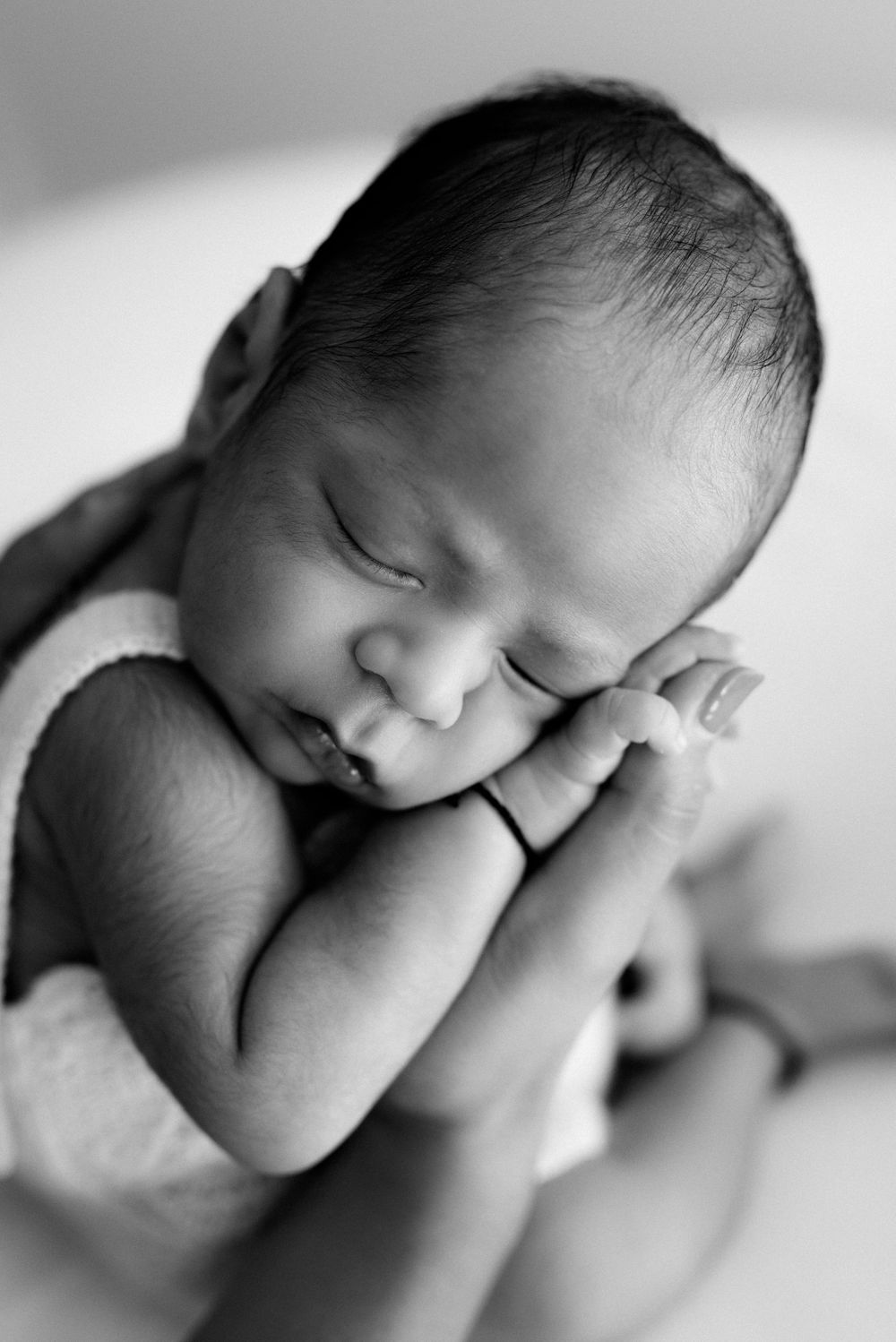 Black and white portrait of sleeping newborn in artistic pose.