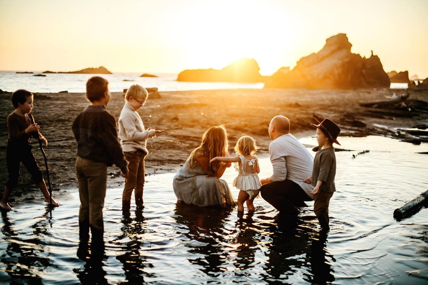 Group gathered on rocky beach at sunset for photography session.