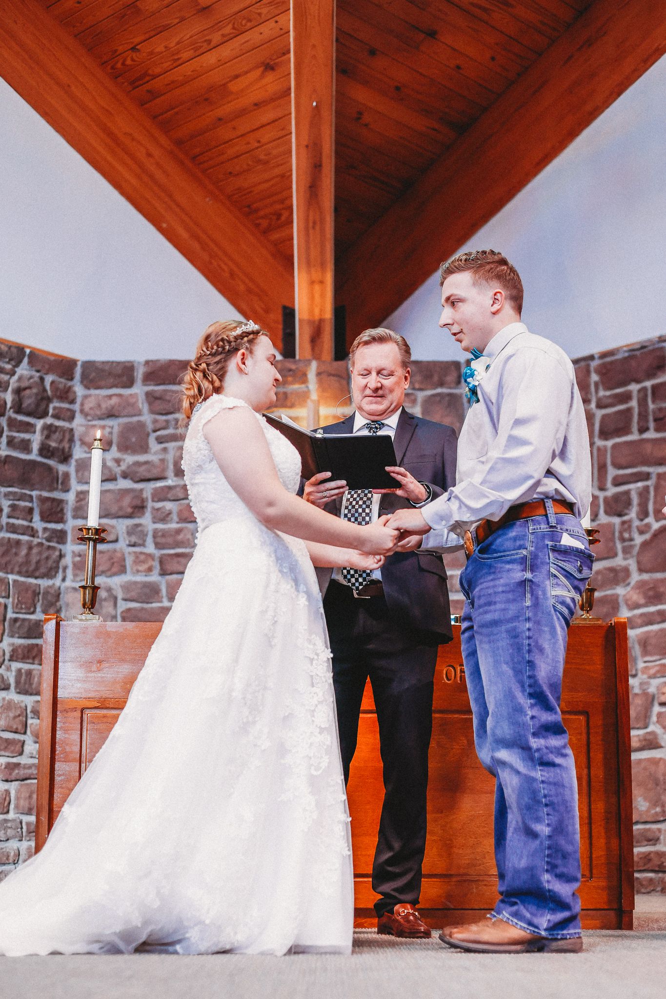 A couple exchanges vows during their wedding ceremony in a stone chapel with wooden beams.