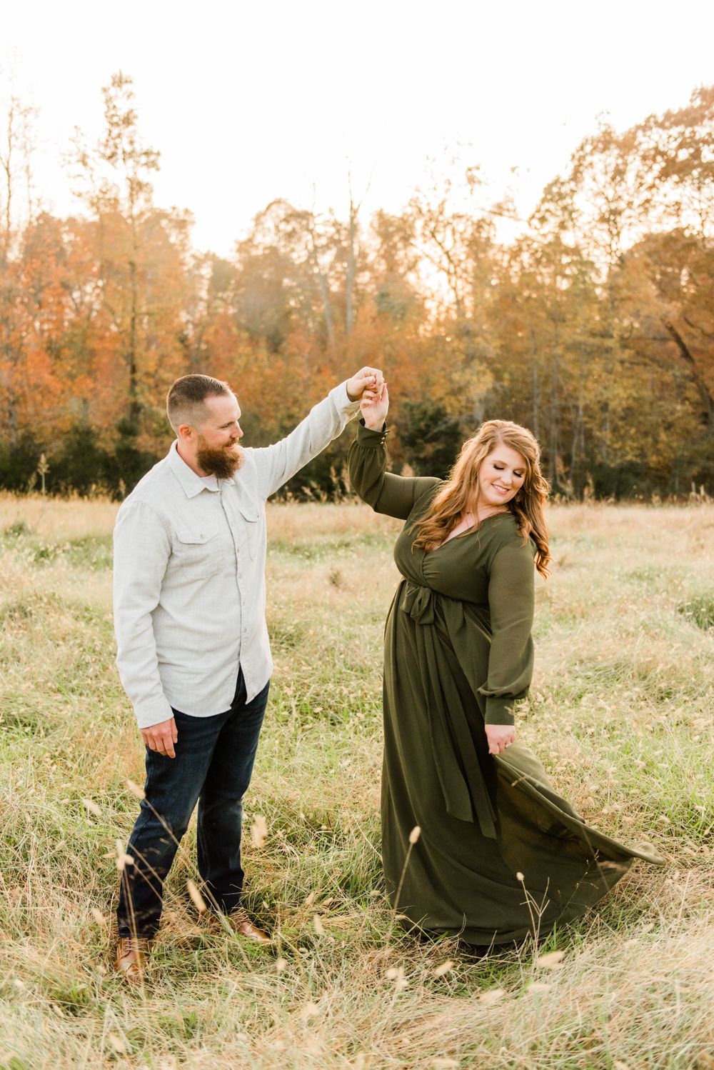 Couple dancing in autumn field during golden hour.