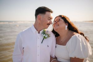 Romantic newlywed couple sharing intimate moment by ocean.