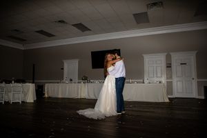 A couple sharing their first dance in an elegant reception hall with white decor.