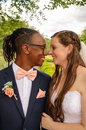 A tender moment between newlyweds in formal attire with peach boutonniere accent.